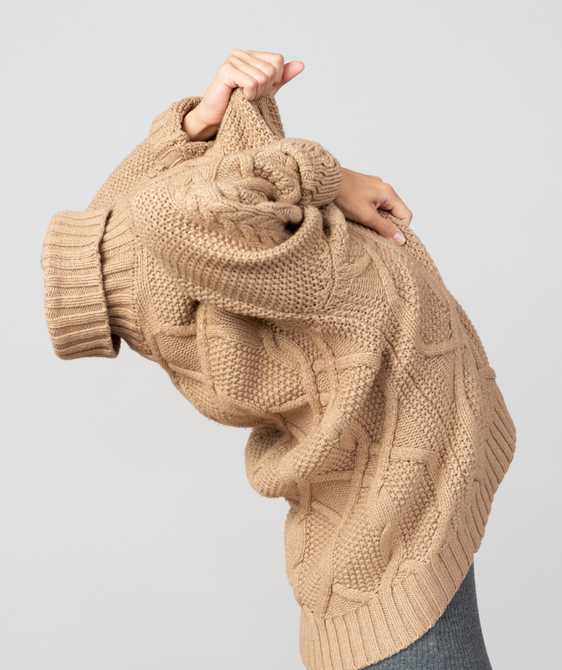 Woman pulling a sweater over her head.