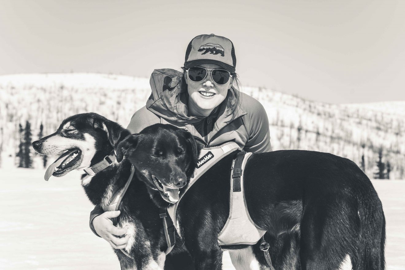 A woman poses with two dogs. It is winter.