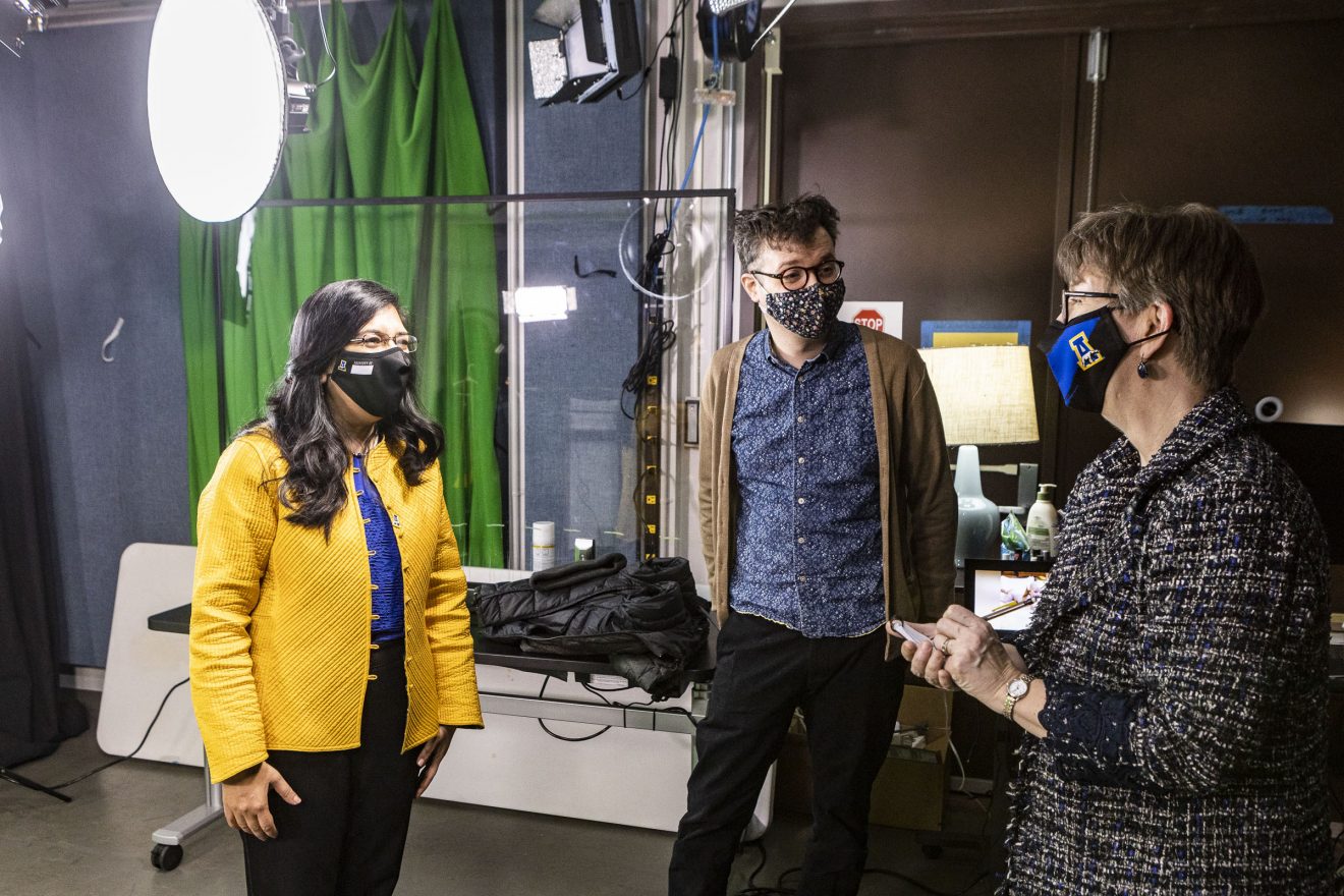 Three people wearing masks standing in a AV studio.