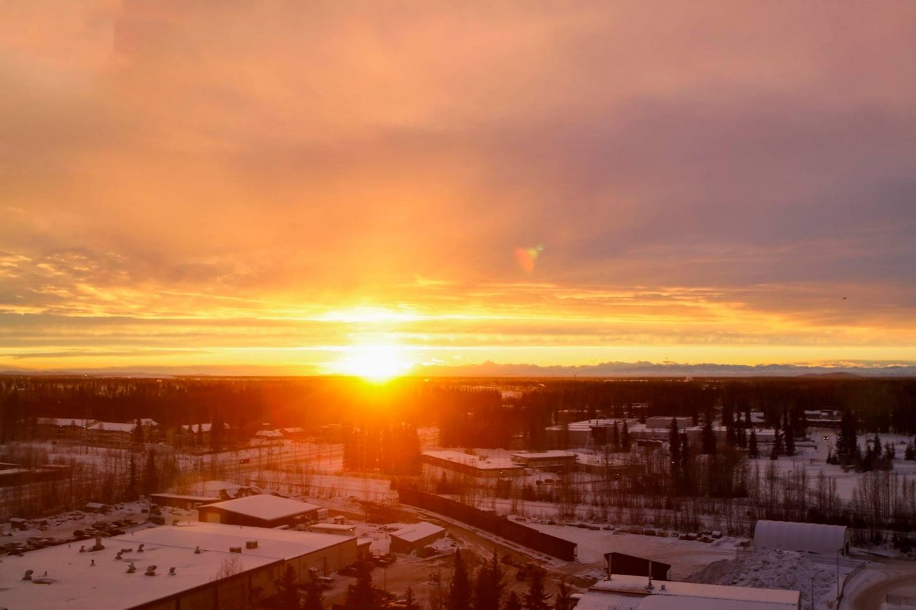 Sun low on the horizon over a snowy campus.