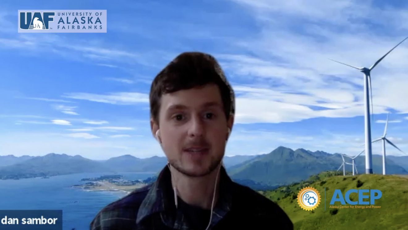 Screenshot of man on a video call talking in front of a backdrop of wind turbines on a hill overlooking mountains and ocean