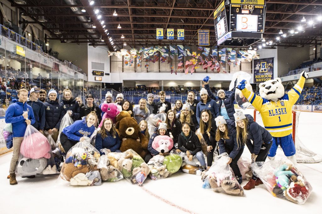 Dozens of people gather on the ice, along with Nanook, with bags of stuffed animals.