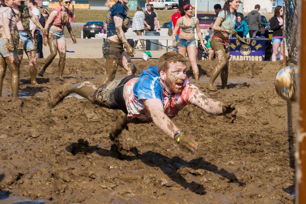 Man diving in the mud for volleyball.