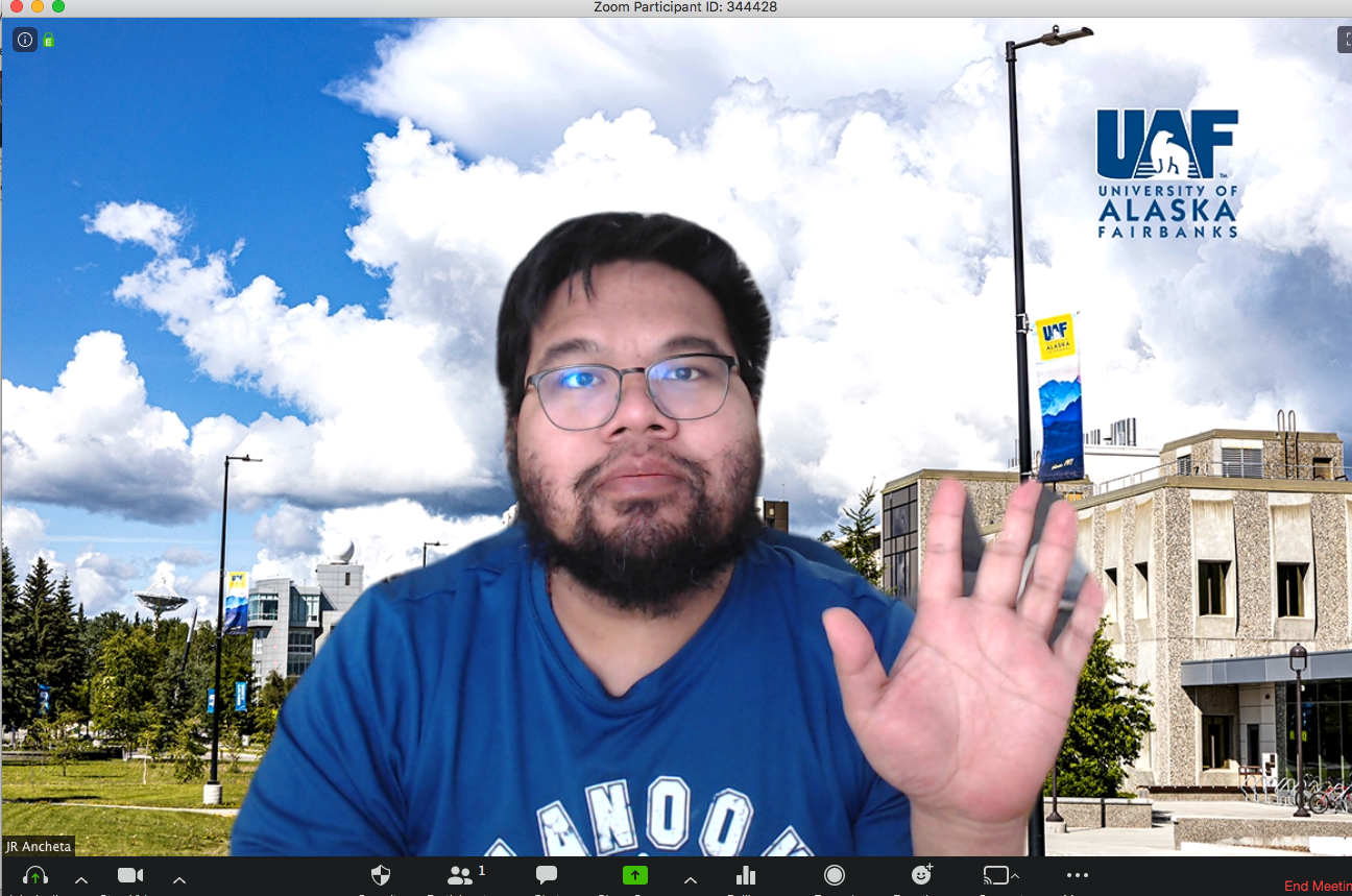 Screen shot of man waving, with background image of West Ridge in summer behind him.