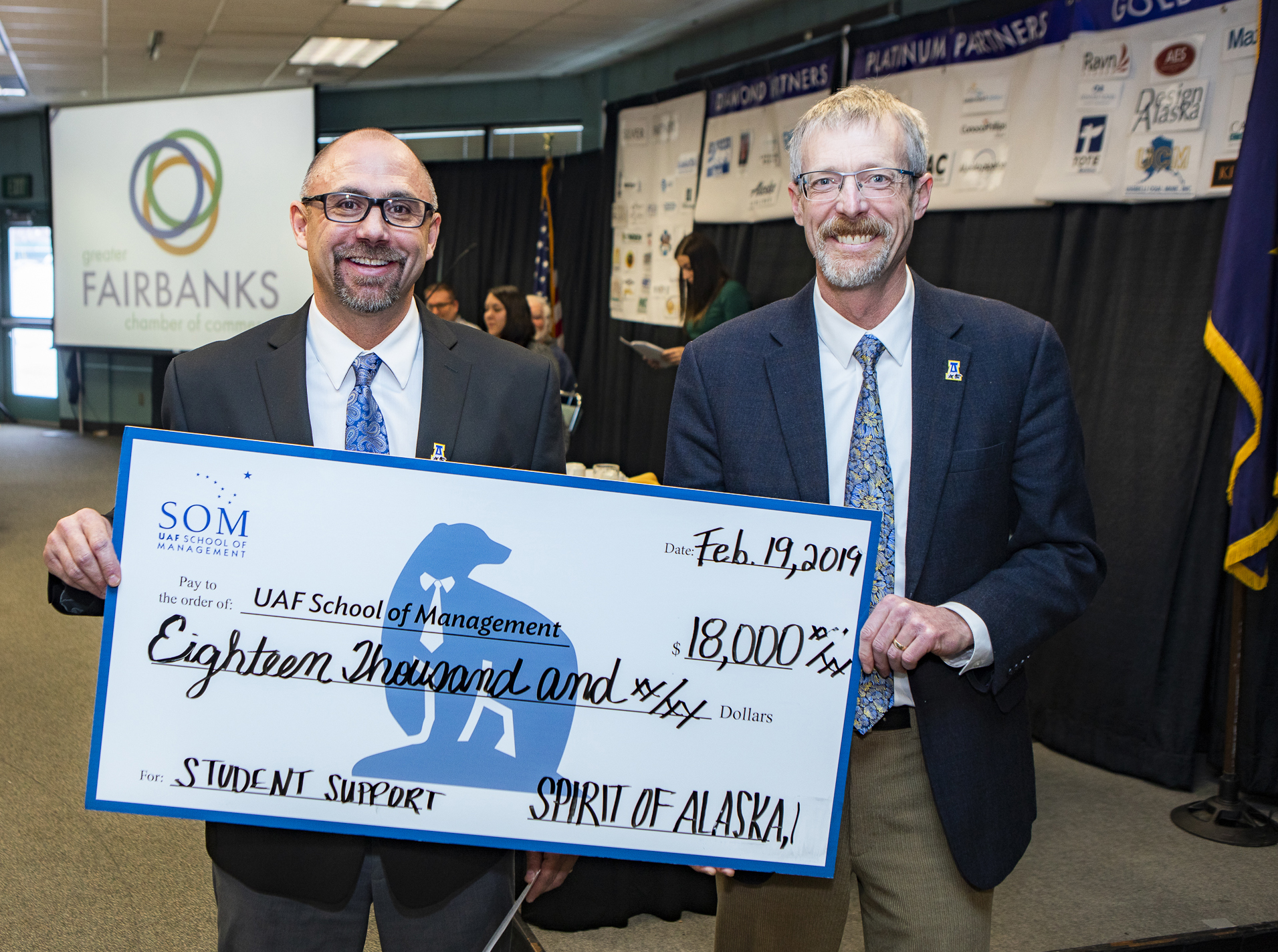 Anthony Rizk, UAF alumnus ’90, ’97, presents a check to UAF Chancellor Dan White at a Greater Fairbanks Chamber of Commerce meeting. Photo by Tammy Tragis-McCook. 