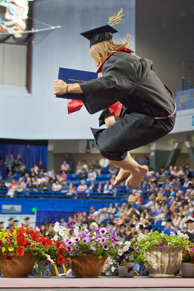 History graduate Caleb Kuntz goes airborne in his bare feet in celebration. | UAF Photo by Todd Paris