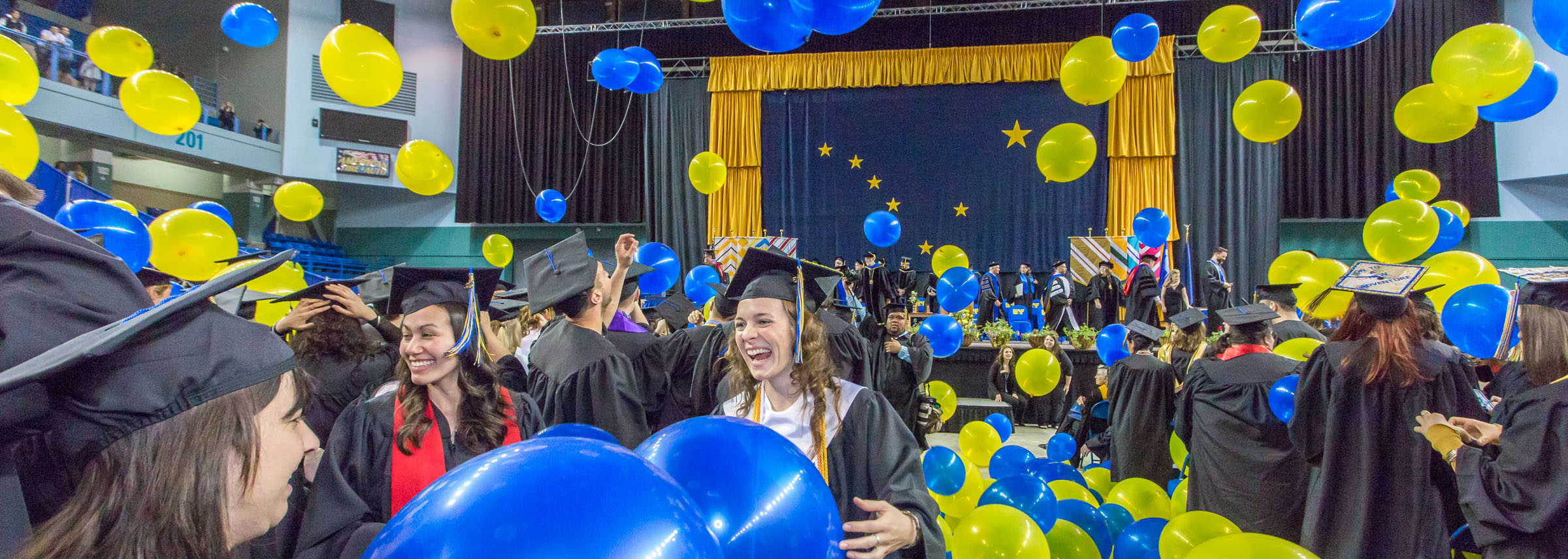 Balloons surround happy graduate at UAF Commencement ceremony.