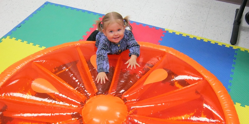Child on a large inflatable orange slice