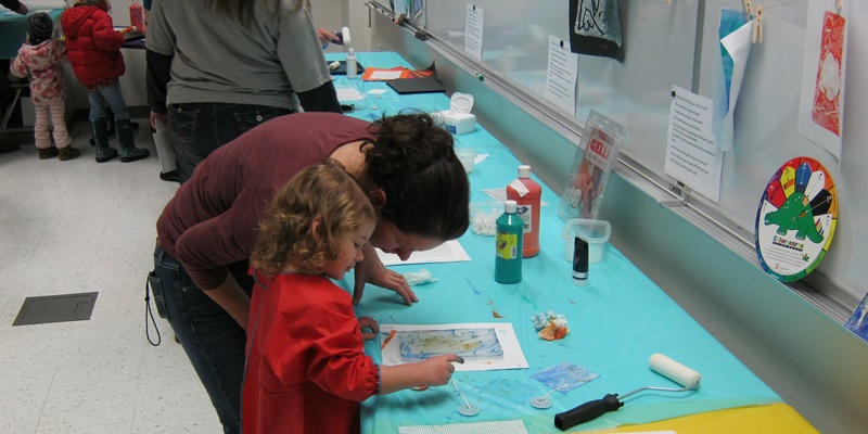 Child and adult make colorful art with paint