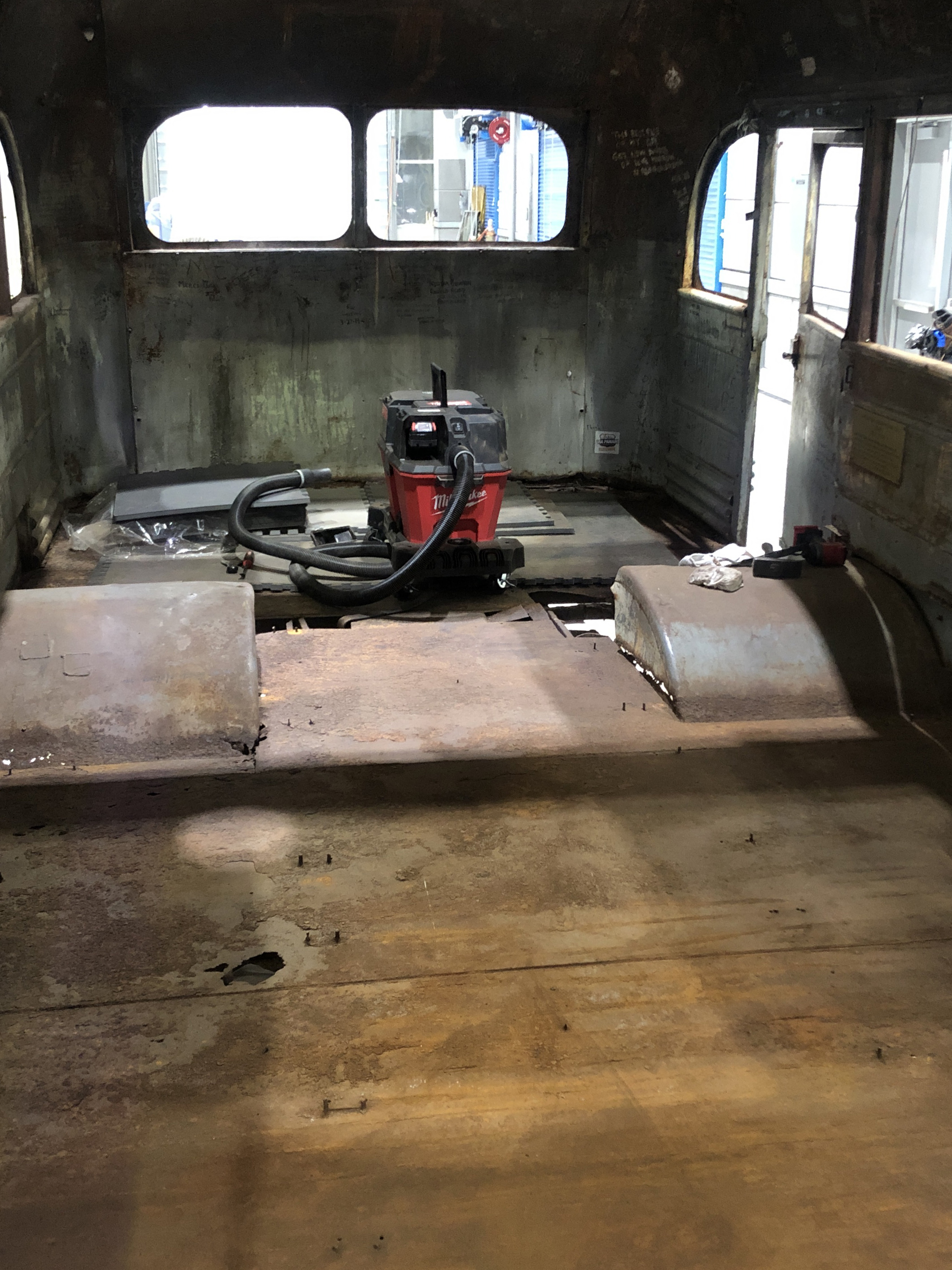 steel bus floor with holes and vacuum resting in back