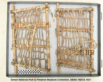 Pair of rectangular snowshoes, made of wooden dowels, sinew, nylon cord, and copper wire. They are lying in a foam-lined drawer, and viewed from above.