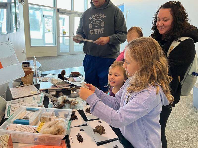 Children looking at a variety of museum objects on a table.