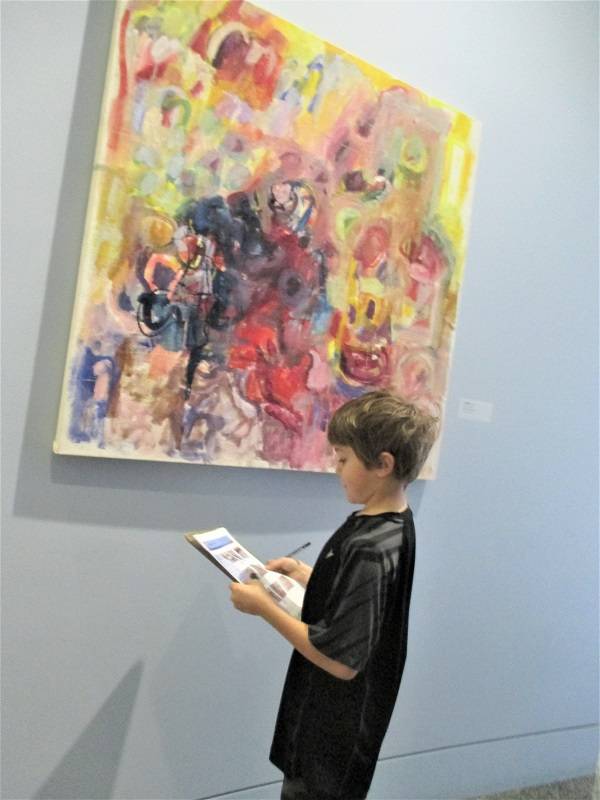 Child looking at a colorful painting in a museum gallery.