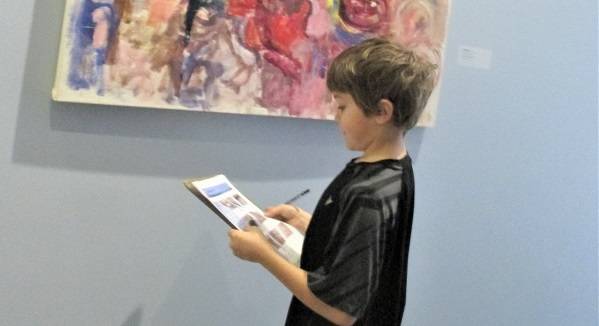 Child looking at a colorful painting in a museum gallery.