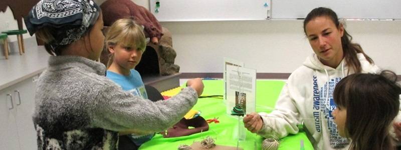 Group of children and adults at a table with craft supplies.