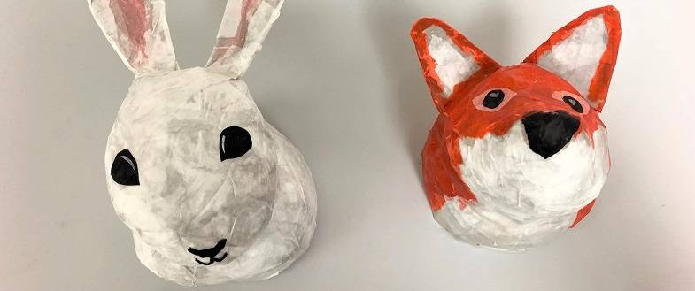 Two paper mache heads, one of a rabbit and one of a fox.