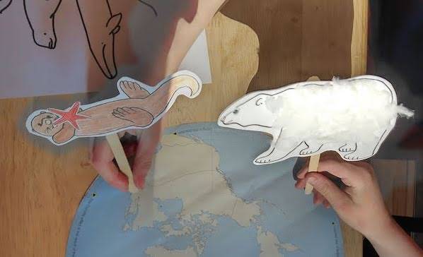 Child's hands playing with sea otter and whale puppets.