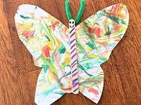 Marbled red, orange and green paper cut into the shae of butterfly wings and glued to a popsicle stick for a body.