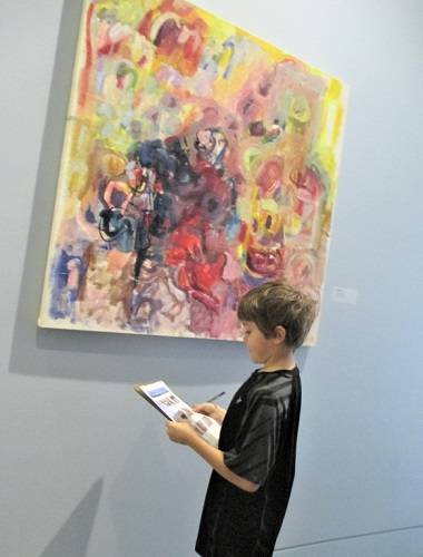 A child looks at a colorful abstract painting by Alfred Skondovitch.