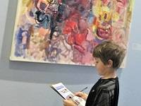 Child looking at a colorful abstract painting by Alfred Skondovitch.