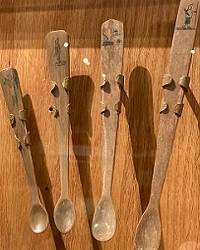 Four small spoons carved from ivory, in a museum display case.