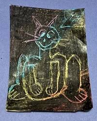 Piece of paper covered in black crayon, with an outline of a cat etched into the crayon, revealing rainbow colors underneath.