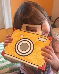 Child holding a toy camera and smiling.