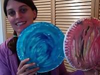 Person holding two paper plates painted to look like planets.