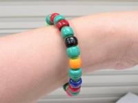 Close-up on a person's wrist wearing a bracelet made of colored beads threaded on a pipecleaner.