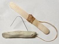 Model fishing lure, made of a long thin piece of clay attached to an unbent paperclip with a length of string. An popsicle stick is attached to the other end of the string.