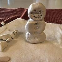 A snowman carved from a ball of tan clay.