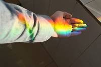 Sunlight shining in rainbow colors on a child's hand.