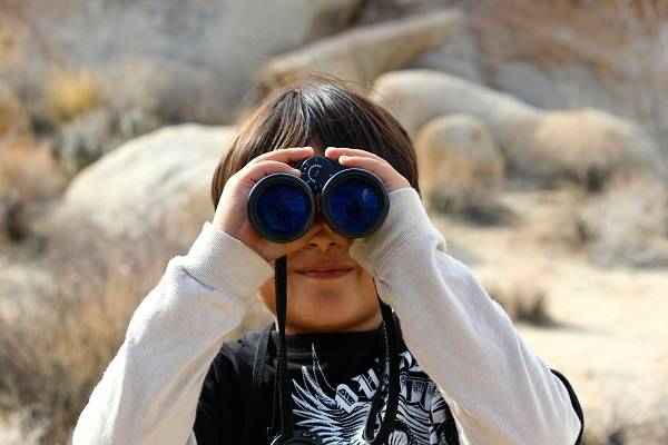 A child holding a pair of binoculars to their eyes.