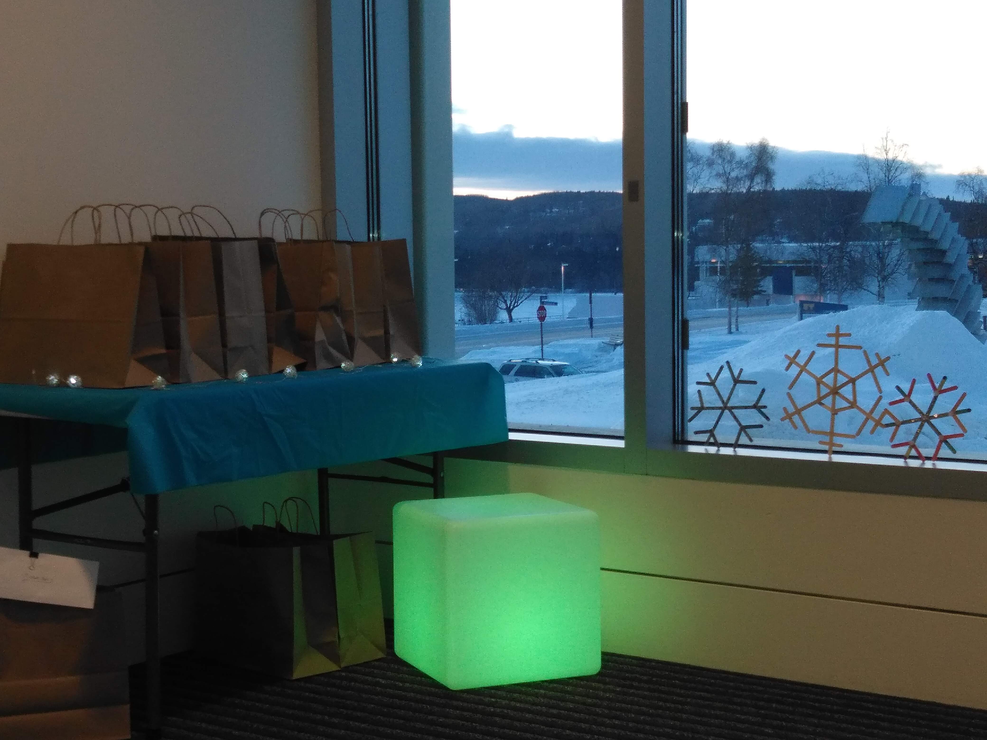 Winter Packets ready for distribution--brown bags on table in entryway, light box & snowflake decorations.