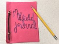 Homemade field journal made out of red construction paper,  with the words "My field journal" on the cover.