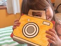 Child holding a toy camera and smiling.