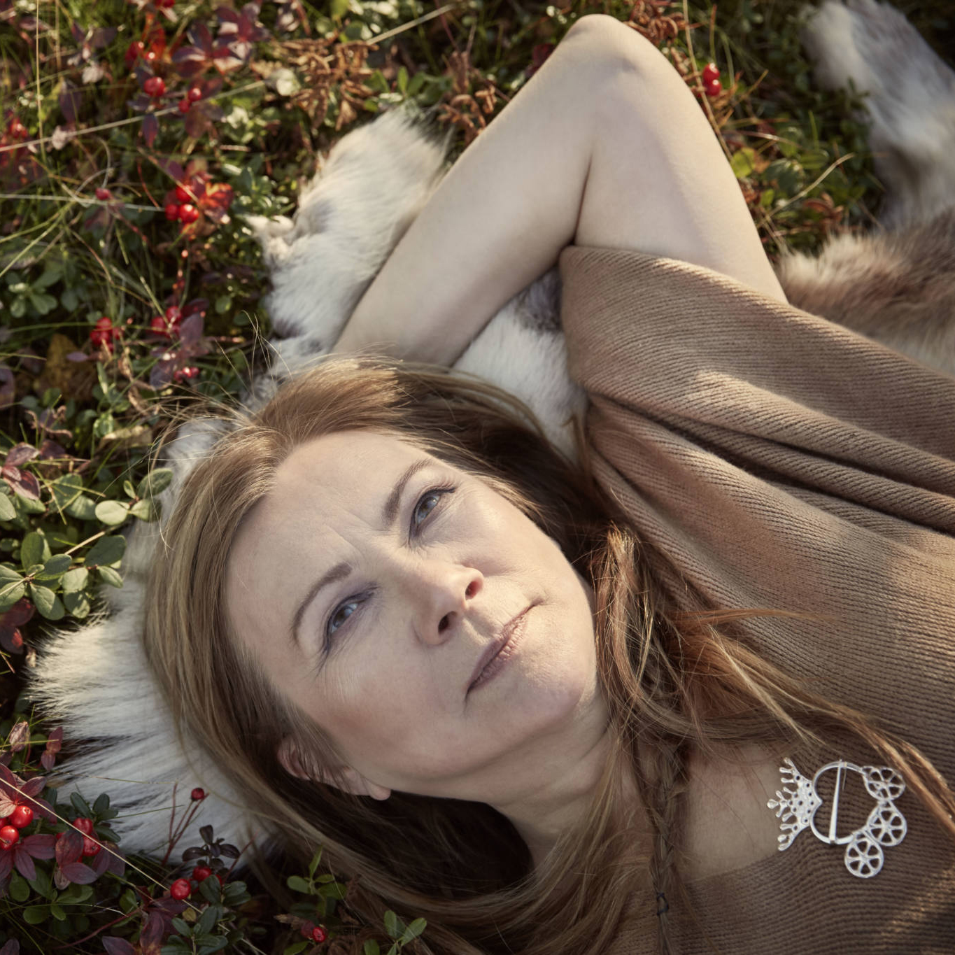 Headshot of Mari Boine laying on the autumn tundra | Photo Credit Gregor Hohenberg