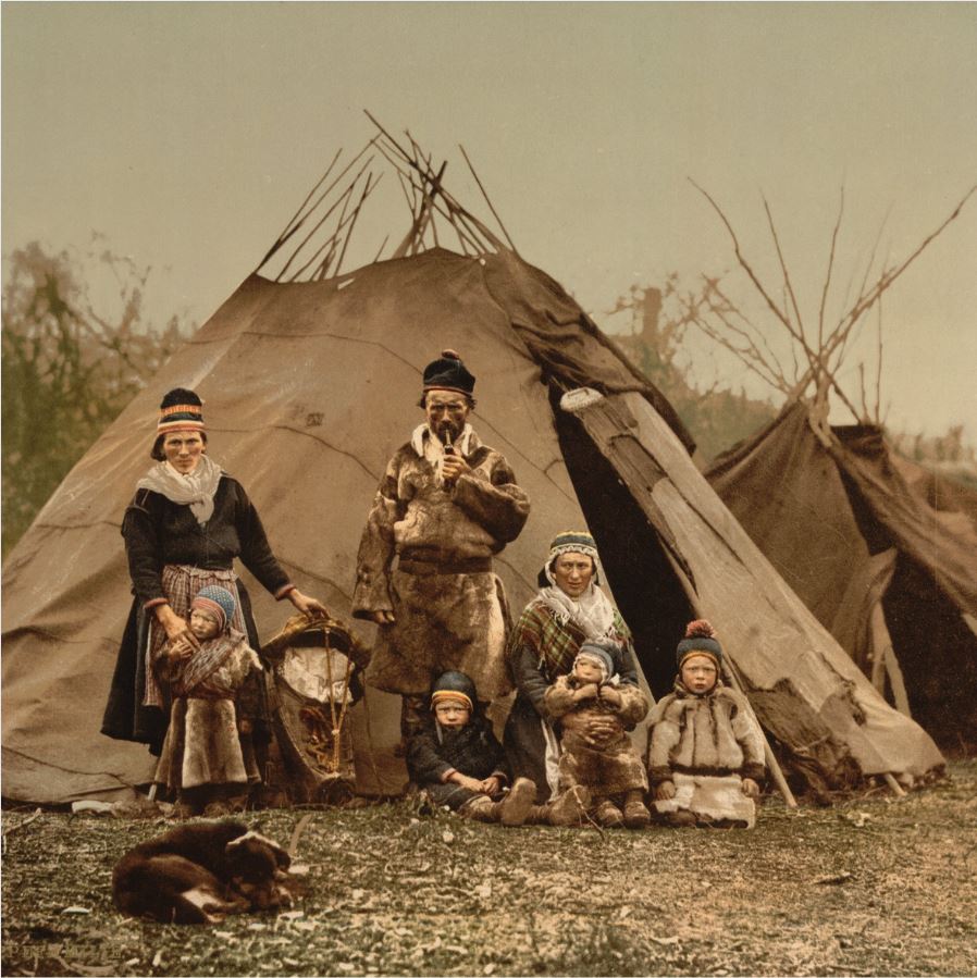 A family of Sámi people in front of their lavvu, with a dog in the foreground. Norway c. 1900