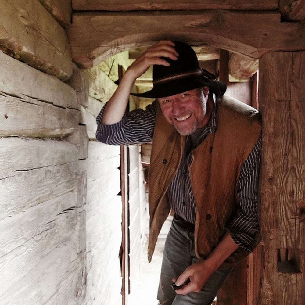 Photo of Magnus Högman in a cowboy hat ducking into a wooden building | YouTube profile photo