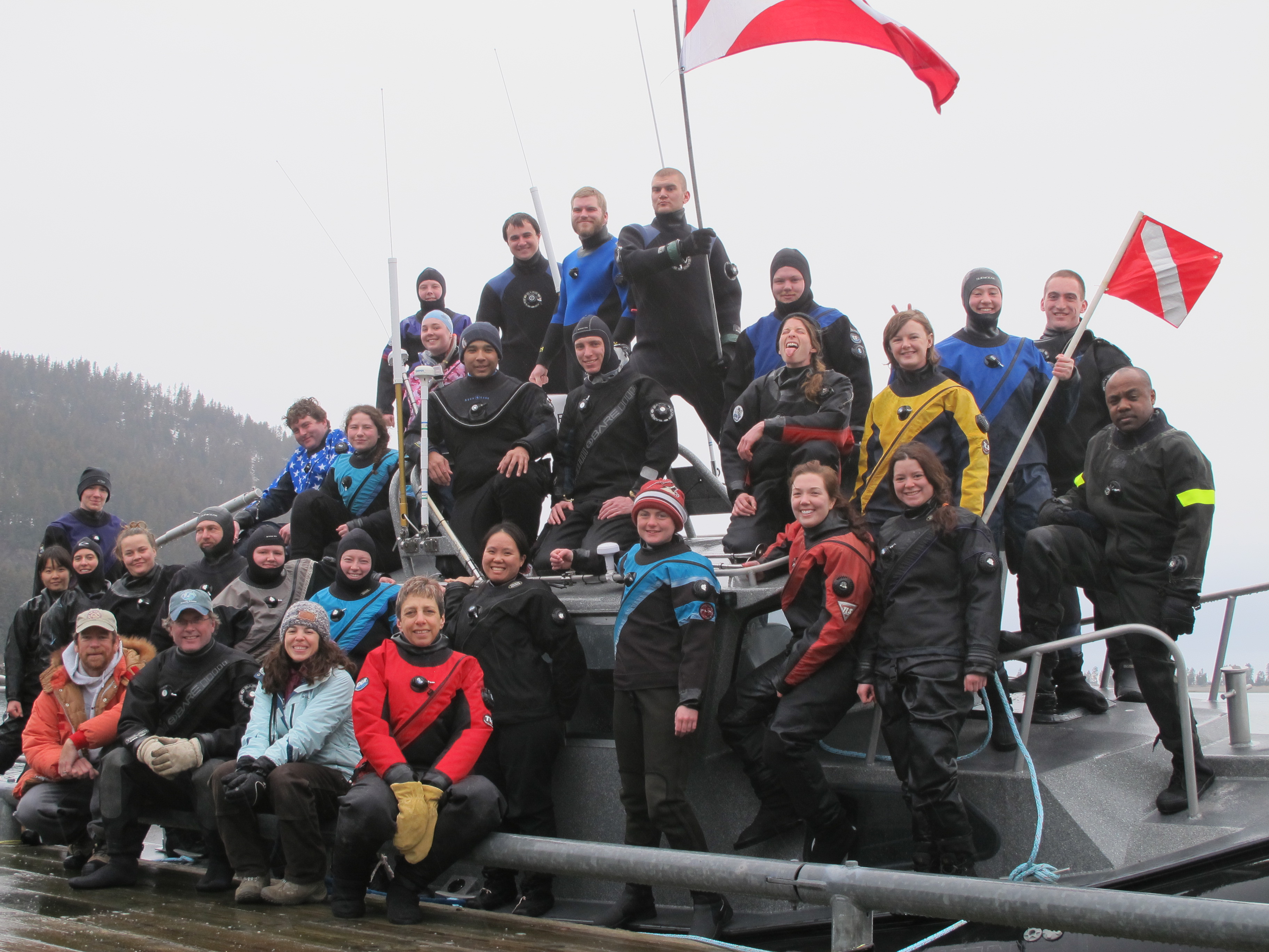 Participants in the UAF School of Fisheries and Ocean Sciences’ 2015 Scientific Diving class gather on the dock and a boat at the Kasitsna Bay Laboratory. The flag is the “diver down flag,” which provides a warning to boat operators and others that people are in the water.