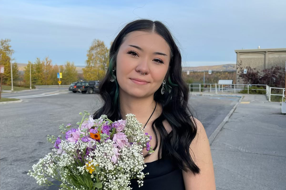 Brenna holds a bouquet of flowers on the UAF Troth Yeddha Campus in Fairbanks