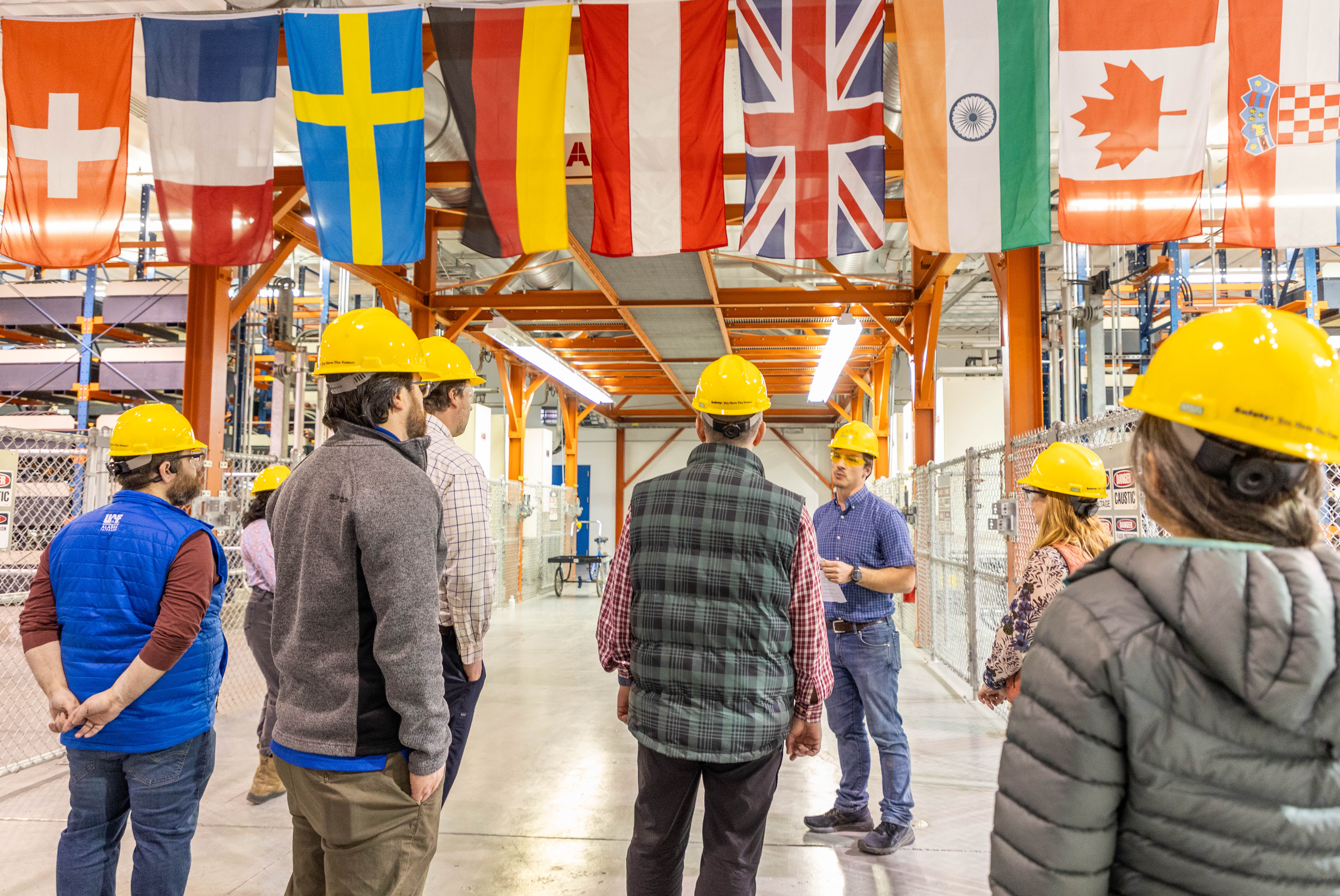 People on a tour stand together in a large industrial building