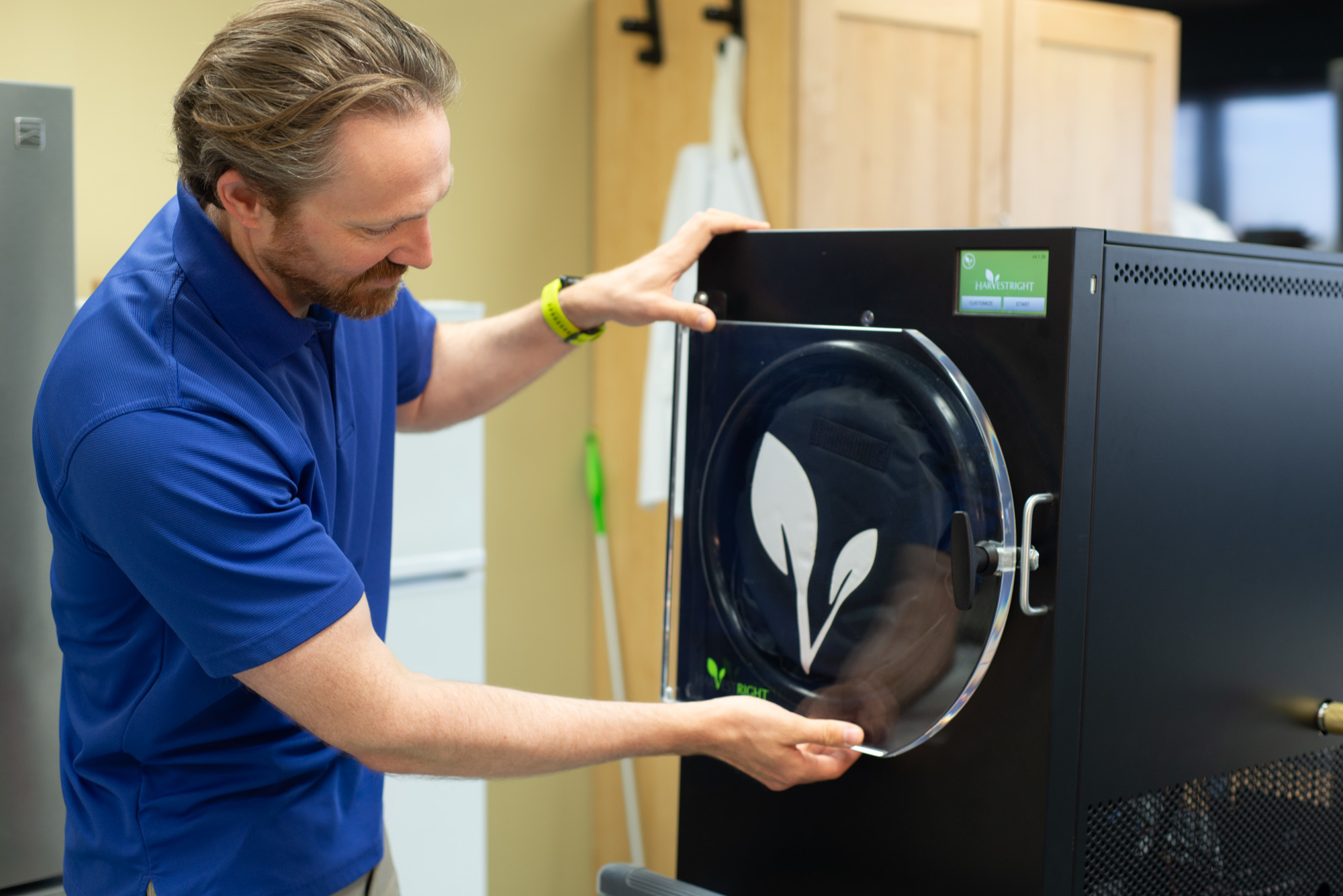 A man adjusts the round door of a large freeze-dryer