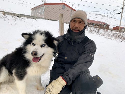 Albert Olick, a tribal officer in the community of Nightmute, poses with his dog, Panda, during a break from assisting with dog vaccinations.