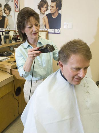 Charlette Lushin is giving Chancellor Steve Jones a haircut.