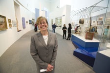 The director of the museum smiles while people in the background view the gallery.