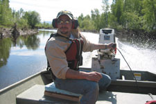 Curtis Knight guides a motorboat down the Kanuti River on a sunny day.