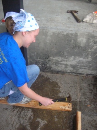 Cynthia Lashinski removes nails from a recycled board, working hard even in the rain. Photo by Clarissa Ribbens