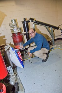 UAF photo by Todd Paris. Andy Soria stands shows some of the components of his research on using fish waste as fuel.