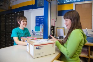 Postal clerk Rachelle Maillard hands over packages to Robin Marshall at the UAF Post Office in Constitution Hall.